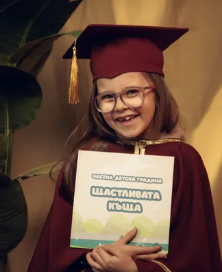 Момиче с абитуриентска шапка държи албума на групата